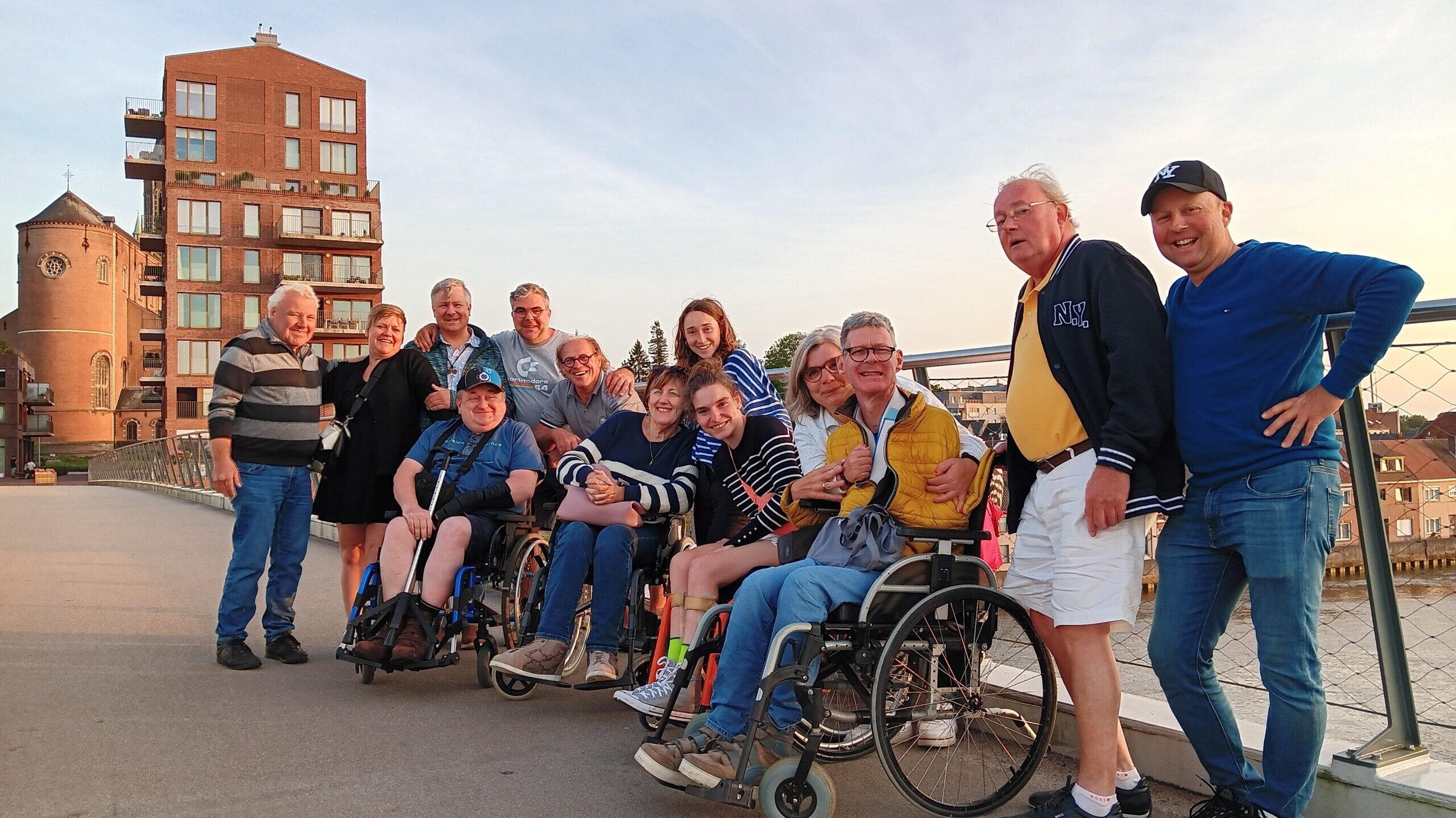 Groep deelnemers poseert op een brug tijdens een groepsuitstap in een stadsomgeving aan het water.
