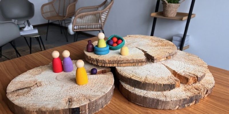 Houten speelfiguren en materialen voor emotionele ondersteuning op tafel.
