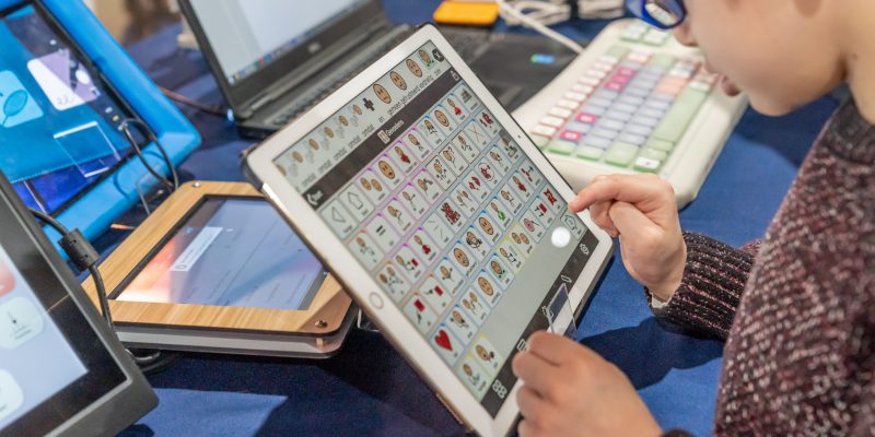 Persoon gebruikt een communicatietablet met pictogrammen.