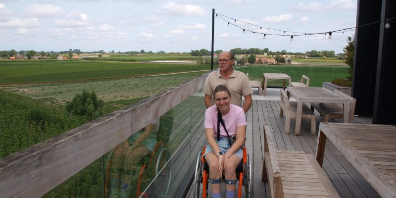 Een jonge vrouw in een rolstoel die wordt geduwd door een man