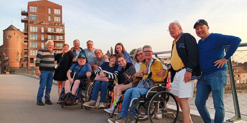 Groep deelnemers poseert op een brug tijdens een groepsuitstap in een stadsomgeving aan het water.